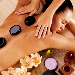 Adult woman having hot stone massage in spa salon. Beauty treatment concept.