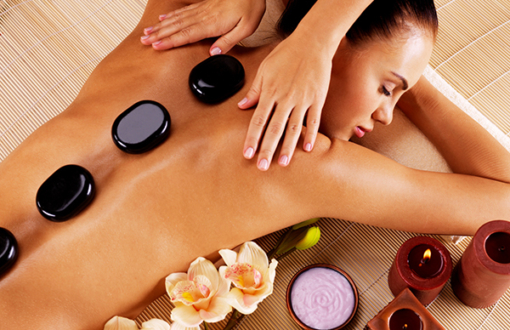 Adult woman having hot stone massage in spa salon. Beauty treatment concept.